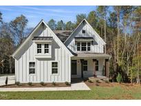 Charming two-story white home featuring board and batten siding, gabled roof, and a welcoming front porch at 842 Magnolia Acres Ln, Fuquay Varina, NC 27526