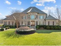 Impressive brick home with stone accents, manicured lawn, and mature landscaping offers stately curb appeal at 1017 Payton Ct, Raleigh, NC 27614