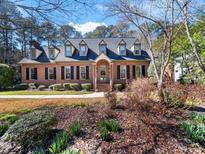 Traditional brick home with a manicured lawn, dormer windows, and a welcoming front entrance at 104 Meadowglades Ln, Cary, NC 27518