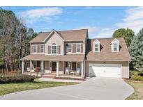 Charming two-story home featuring a welcoming front porch, attached garage, and well-maintained landscaping at 104 Spooner Ct, Holly Springs, NC 27540