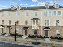 Charming townhomes with a combination of tan siding and brick exteriors and black door and roof accents at 1414 Excelsior Grand Ave, Durham, NC 27713