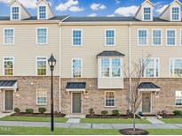 Charming townhome featuring a brick facade, covered doorways, and beautifully landscaped front yard at 1414 Excelsior Grand Ave, Durham, NC 27713