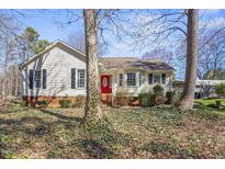 Charming home featuring a red front door, complemented by black shutters and mature trees at 152 Rynal Dr, Garner, NC 27529