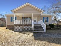 Charming home featuring a covered front porch with white railing and blue shutters, enhancing curb appeal at 207 Lawrence St, Fuquay Varina, NC 27526