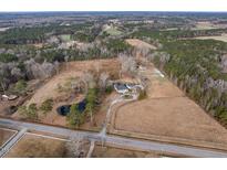 Stunning aerial view of acreage with a home, pond, long driveway, and beautiful surrounding landscape at 4063 Nc-39, Selma, NC 27576
