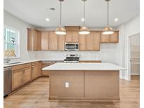 Bright kitchen features a center island, stainless appliances, pendant lighting, and plenty of cabinet storage at 608 Hyperion Aly, Wake Forest, NC 27587