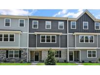 New construction townhome featuring gray siding, brick accents, and a well-manicured lawn under a clear blue sky at 2241 Horton Park Dr, Apex, NC 27539