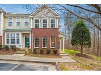 Charming two-story townhome featuring brick accents, a well-manicured lawn, and a welcoming green front door at 4555 Sugarbend Way, Raleigh, NC 27606