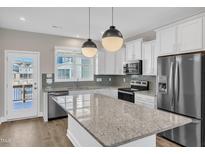 Bright kitchen with stainless appliances, white cabinets, granite countertops, and a center island at 507 Gateway Townes Blvd, Wake Forest, NC 27587