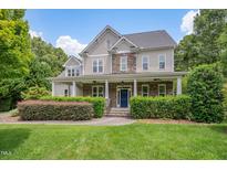 Charming two-story home with a stone and siding exterior, a covered porch, and manicured landscaping at 7400 Bleasdale Ct, Apex, NC 27539