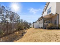 View of backyard featuring a screened-in porch, mature trees, and an expansive grassy area at 415 Mariah Towns Way, Garner, NC 27529