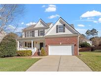 Charming two-story home with a brick facade, manicured lawn, and attached two-car garage at 104 Riley Oaks Ln, Apex, NC 27539