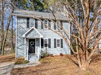 Charming two-story home with light blue siding and a welcoming front entrance in a wooded landscape at 1112 Chalk Level Rd, Durham, NC 27704