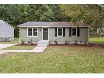 Charming single-story home featuring manicured landscaping, a gray color scheme, and a welcoming entryway at 1213 Freeman Dr, Sanford, NC 27330