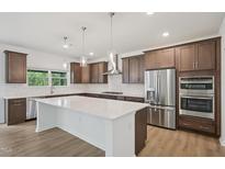 A spacious kitchen features stainless steel appliances, dark wood cabinets, and a large white countertop island at 167 S Harvest Ridge Way # Homesite 223, Wilson's Mills, NC 27520