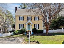 Charming yellow two-story home with a well-manicured lawn and a white picket fence at 1820 Carrington Dr, Raleigh, NC 27615