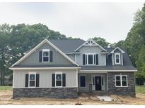 Charming two-story home with stone accents and a neatly landscaped yard under a cloudy sky at 1663 Keith Hills Rd, Lillington, NC 27546