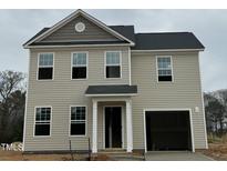 Charming two-story home with light siding, a dark roof, and an attached garage, offering classic curb appeal at 260 Johnson Ridge Way, Four Oaks, NC 27524