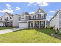 Beautiful gray two-story home featuring manicured lawn, a two-car garage, and a classic covered front porch at 267 N Maple Walk Dr # 217, Garner, NC 27529