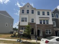 Beautiful townhome featuring a mixed material facade with brick and white siding, a manicured lawn, and professional landscaping at 312 Chesapeak Commons St # 144, Garner, NC 27529