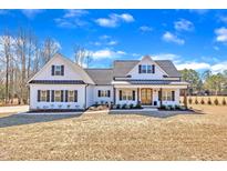 Charming farmhouse exterior with a covered front porch, white siding, black shutters, and a well-manicured lawn at 3608 Buzzard Rd, Wendell, NC 27591