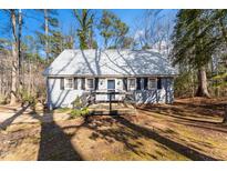 Charming cottage-style home featuring a metal roof, black shutters, and inviting front porch at 365 Shawnee Dr, Louisburg, NC 27549
