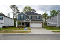 Charming two-story home with a brick and siding facade, attached garage, and well-manicured front yard at 3821 Rosebush Dr, Zebulon, NC 27597