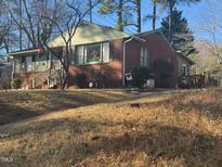 Charming brick home with green siding accents and inviting front porch nestled among mature trees at 402 Willow St, Cary, NC 27511