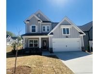 Charming two-story home featuring a two-car garage, light gray siding, and a well-manicured front lawn under a clear blue sky at 5161 Church Rd # 17, New Hill, NC 27562