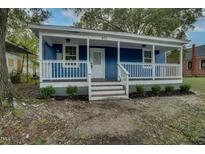 Charming blue house with a covered front porch, white railings, and landscaped front yard at 915 E Holly St, Rocky Mount, NC 27801