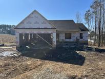 Unfinished single Gathering home with a two car garage and a dark colored roof, surrounded by dirt and trees at 189 Rye Way, Wendell, NC 27591