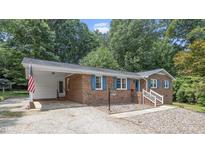 Charming single-story brick home featuring blue shutters, a covered carport, and a well-maintained gravel yard at 2409 Parkway Dr, Raleigh, NC 27603