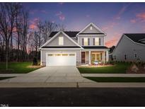 Charming two-story home with a well-manicured lawn and a two-car garage, under a twilight sky at 632 Emerald Bay Cir, Raleigh, NC 27610