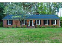 Charming brick home featuring a manicured lawn and classic black shutters at 711 Stuart Dr, Sanford, NC 27330
