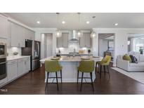 This open kitchen features gray cabinets, stainless steel appliances, and a large center island with pendant lighting at 812 Emerald Bay Cir, Raleigh, NC 27610