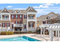 Beautiful townhome exterior view showcases double balconies and red shutters near a refreshing community pool at 10321 Sablewood Dr # 108, Raleigh, NC 27617