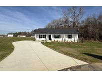 Charming single-story home with a white exterior, black shutters, and a long concrete driveway at 107 Faucette Dr, Selma, NC 27576