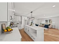 Modern white kitchen with a large island and stainless steel appliances opens to the living room, creating a spacious feel at 1204 Donphil Rd, Durham, NC 27712