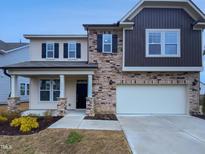 Two-story home featuring a stone facade, beige siding, black shutters, and an attached two-car garage at 1336 Weavers Trace Dr, Zebulon, NC 27597