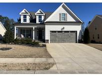 Charming two-story home with gray trim, a front porch and a gray garage door at 145 Plantation Dr, Youngsville, NC 27596