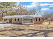 Charming single-story brick home with a metal roof, covered parking, and a welcoming front porch at 1702 Nc 242 N, Benson, NC 27504