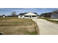 Charming single-story home with a well-manicured lawn and a long concrete driveway, all under a bright blue sky at 57 Faucette Dr, Selma, NC 27576