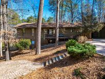 Charming exterior elevation with a brick foundation, tiered garden, and a private setting among mature trees at 748 Shady Lawn Rd, Chapel Hill, NC 27514