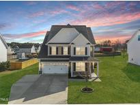 Two-story home featuring a two-car garage, and a well manicured front yard during a beautiful sunset at 140 Southern Acres Dr, Fuquay Varina, NC 27526