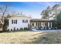 Charming painted brick home with a cozy covered front porch and manicured lawn at 217 Northfield Dr, Raleigh, NC 27609