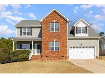 Charming two-story home featuring a brick facade, gray siding, and a well-maintained front yard at 24 Carter Dr, Sanford, NC 27332