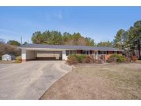Charming one-story brick home with an attached carport and well-maintained front yard landscaping at 6605 Pearces Rd, Louisburg, NC 27549