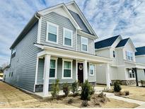 Charming two-story home with a welcoming front porch and attractive gray siding under a partly cloudy sky at 1981 Rosedale Ridge Ave, Wake Forest, NC 27587