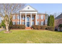 Stately brick home with large columns, black shutters, and well-maintained landscaping on a sunny day at 2110 Crigan Bluff Dr, Cary, NC 27513