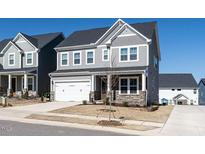 Charming two-story home featuring gray siding, stone accents, and a two-car garage on a sunny day at 353 Murray Grey Ln, Wake Forest, NC 27587